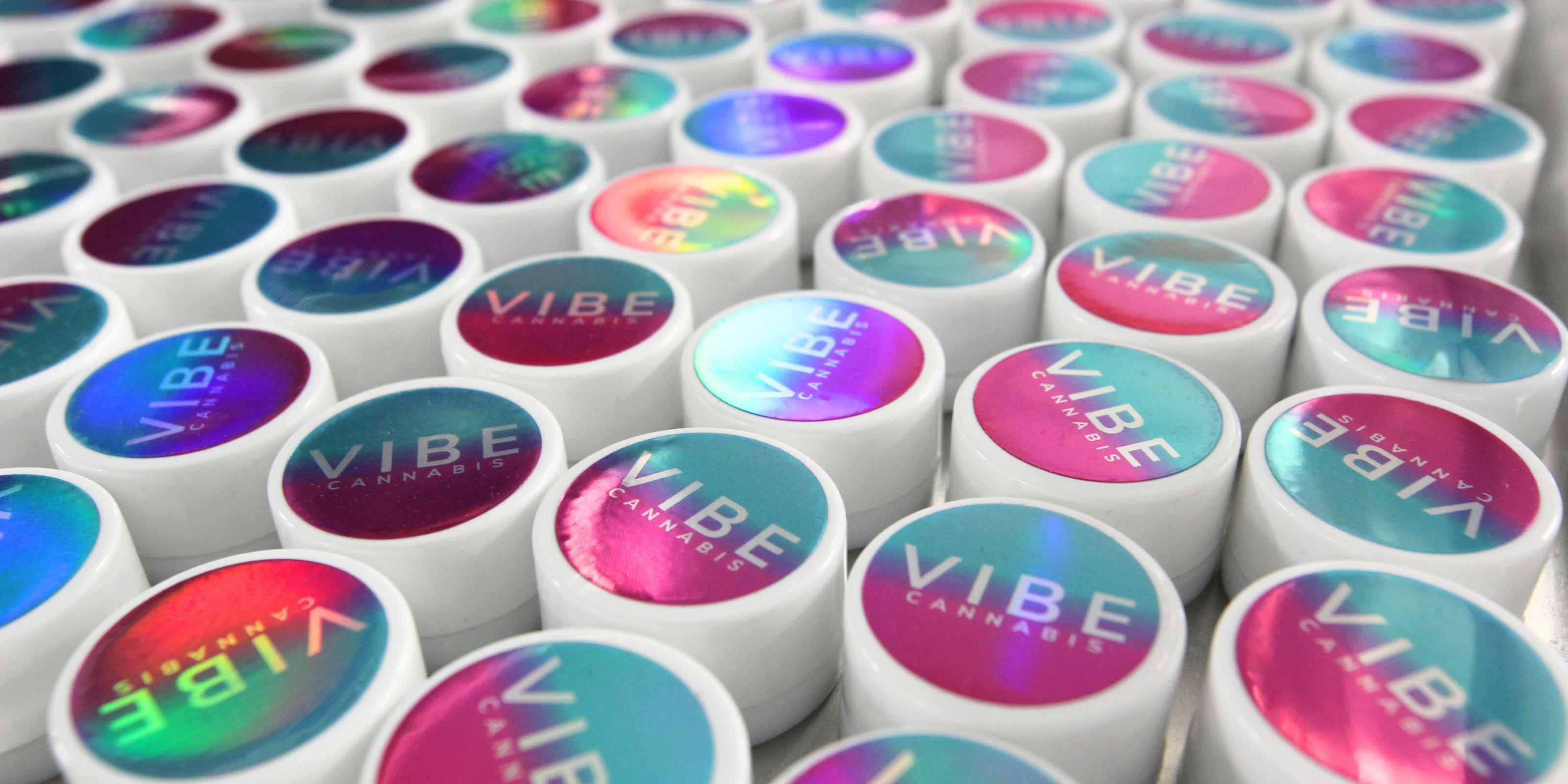 white concentrate jars with a holographic VIBE cannabis branded lid labels